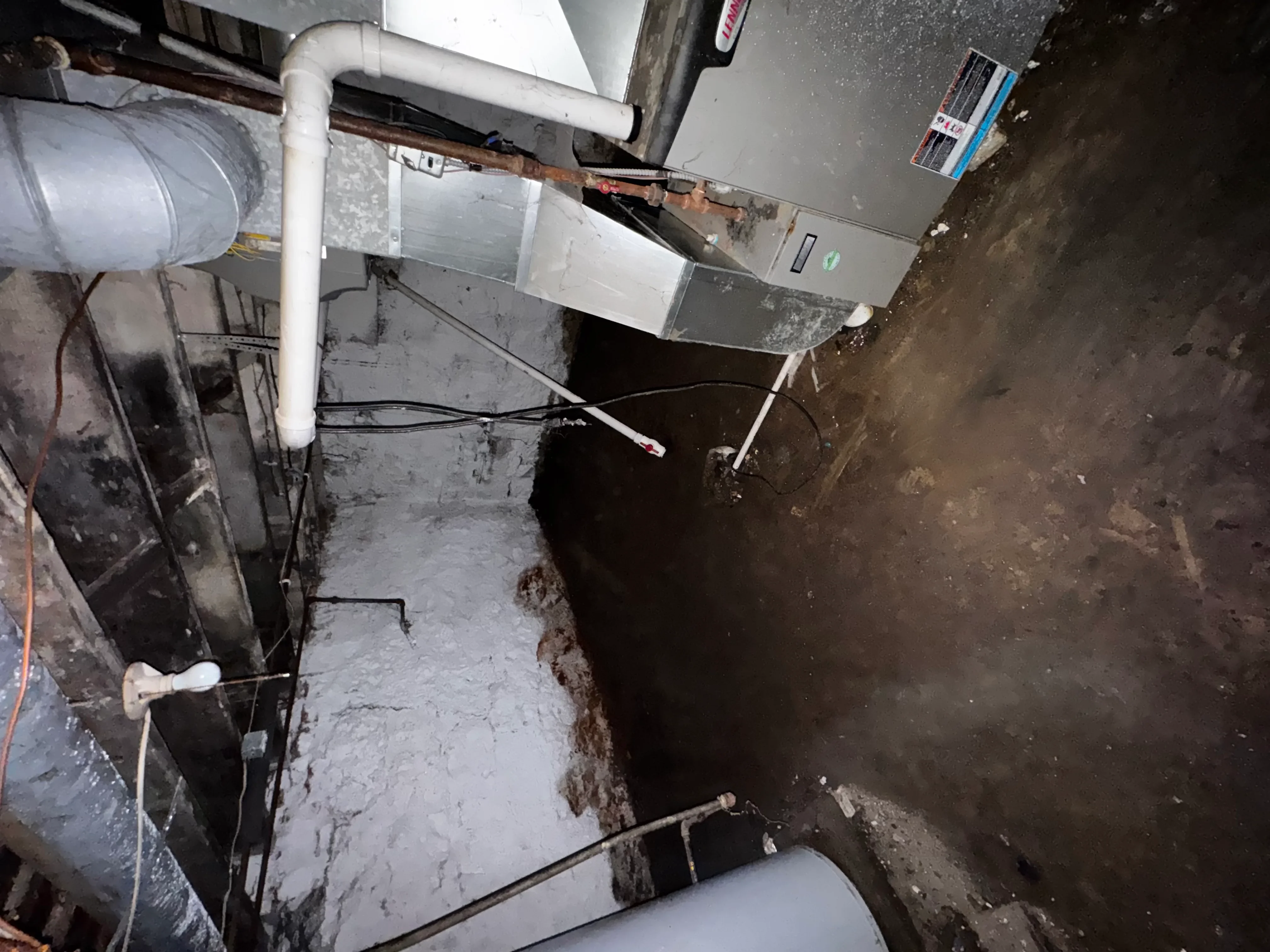 Basement plumbing installation with white PVC pipes and sump pump system