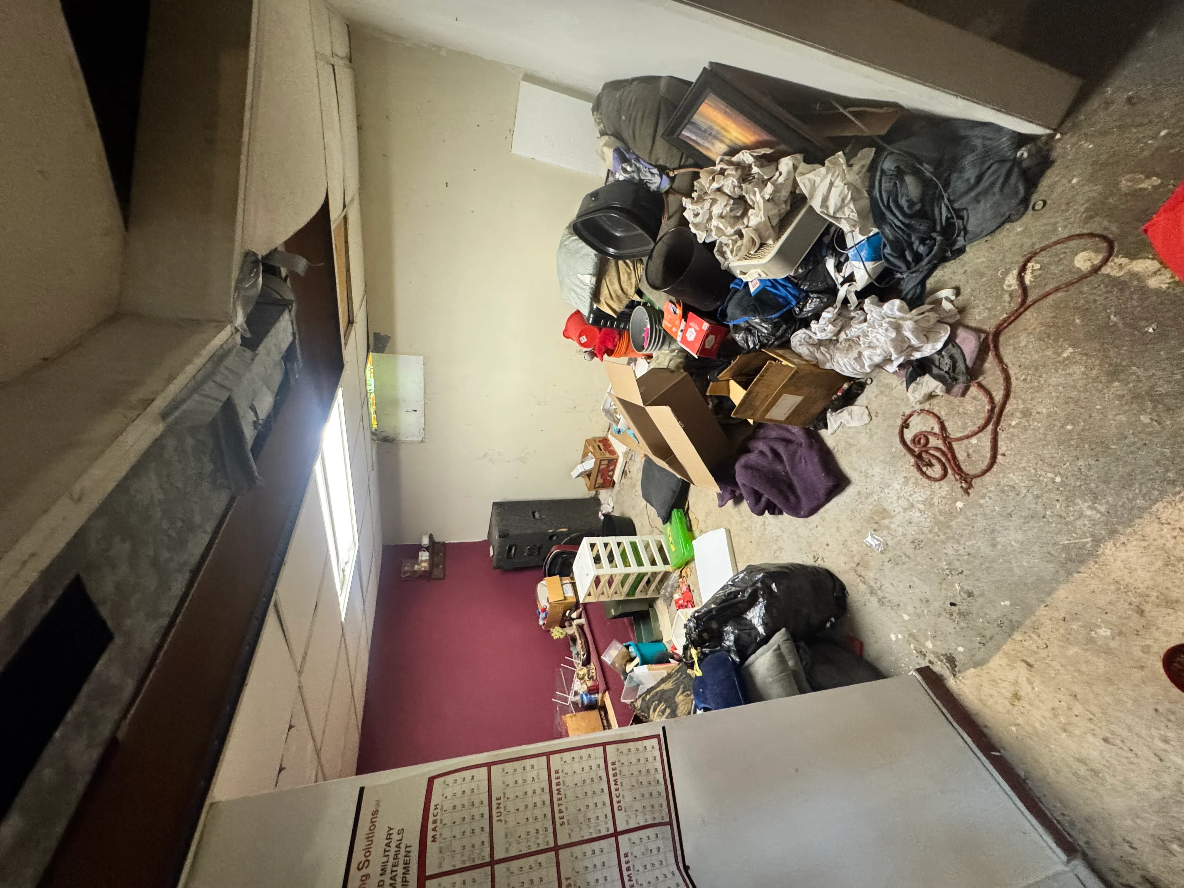 Cluttered residential room with boxes, clothing, and household items cleared during junk removal service