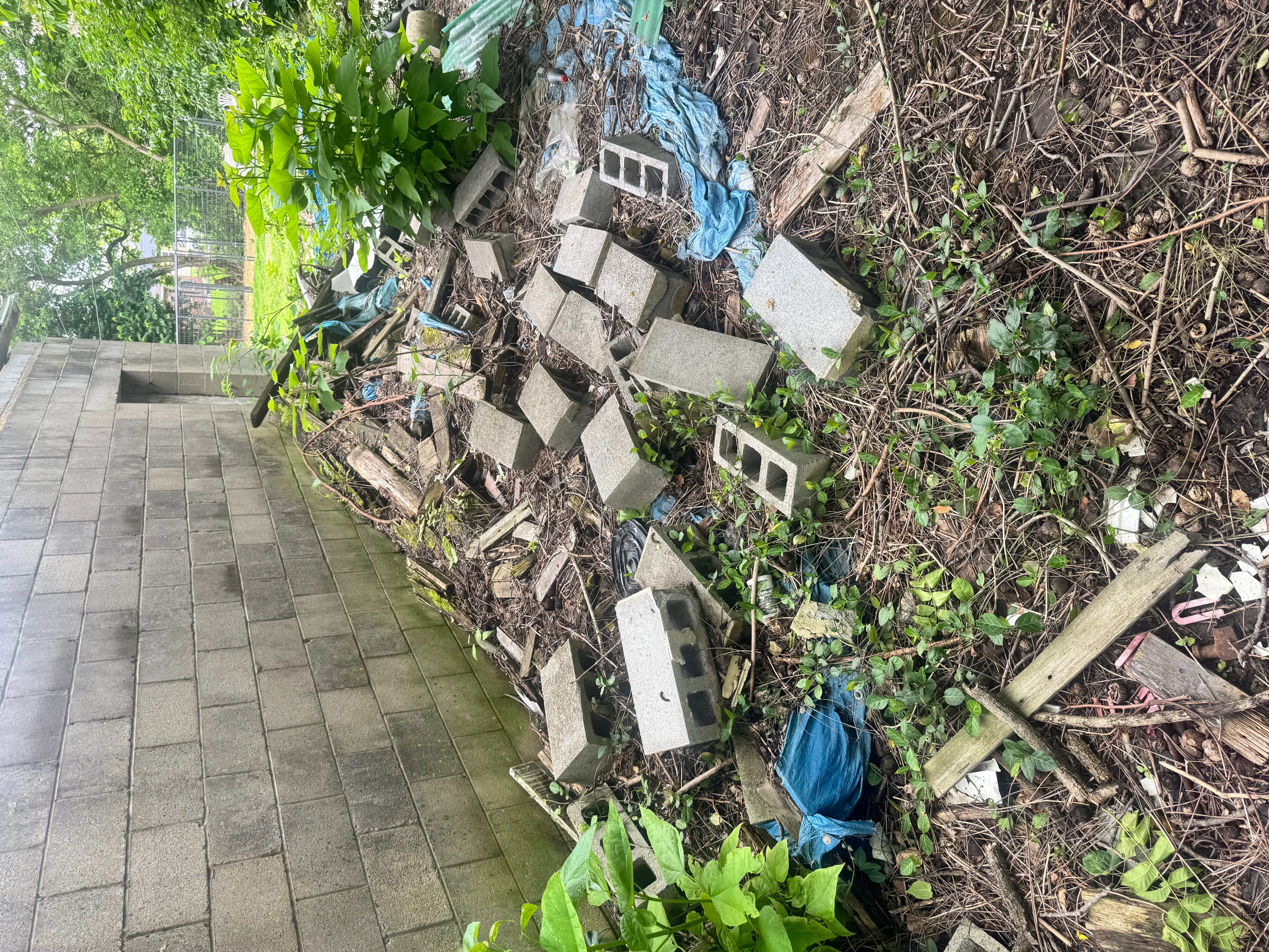 Concrete block retaining wall with new construction alongside cleared landscape area