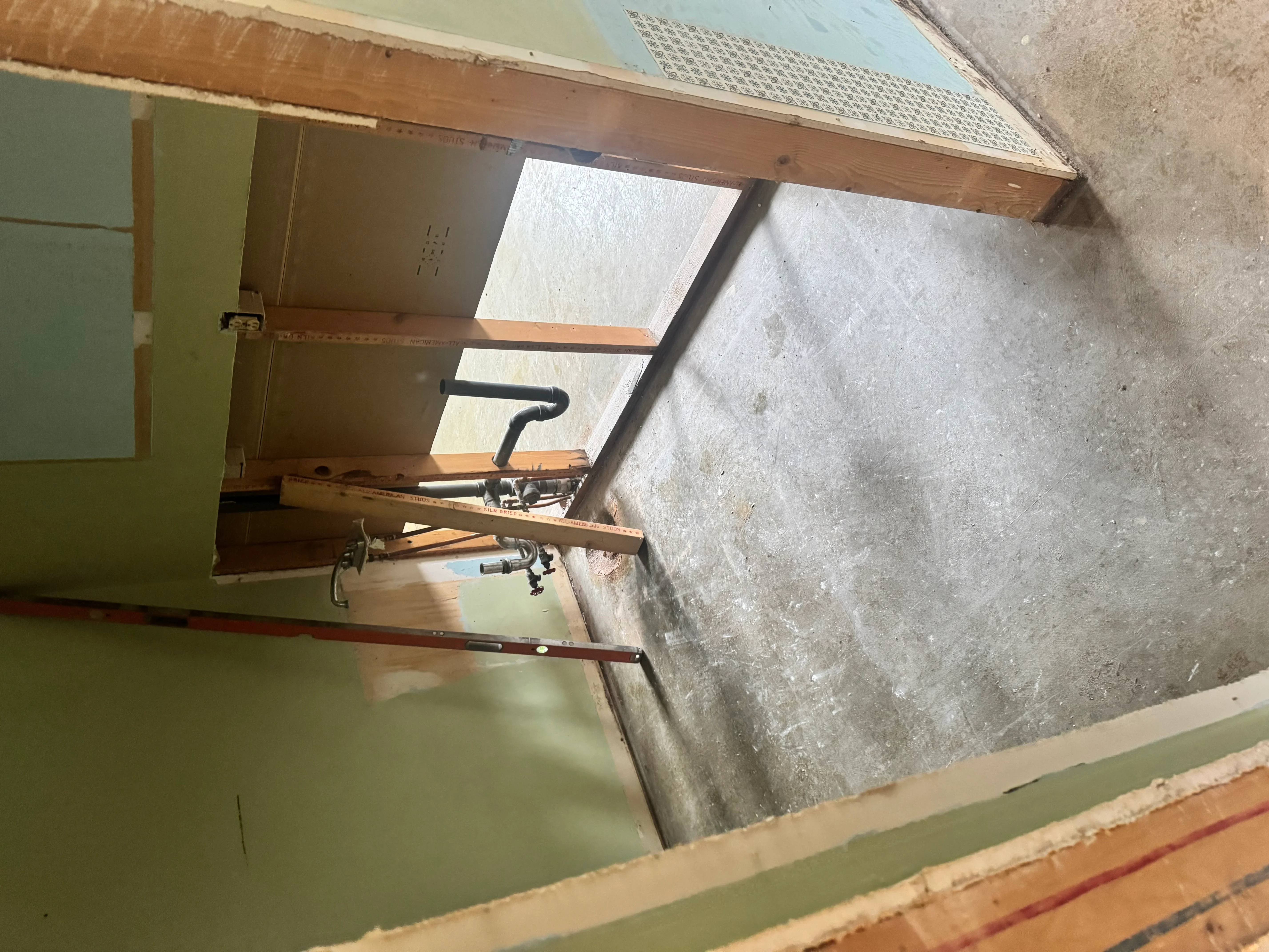 Attic framing project with wooden studs, drywall panels, and skylight opening