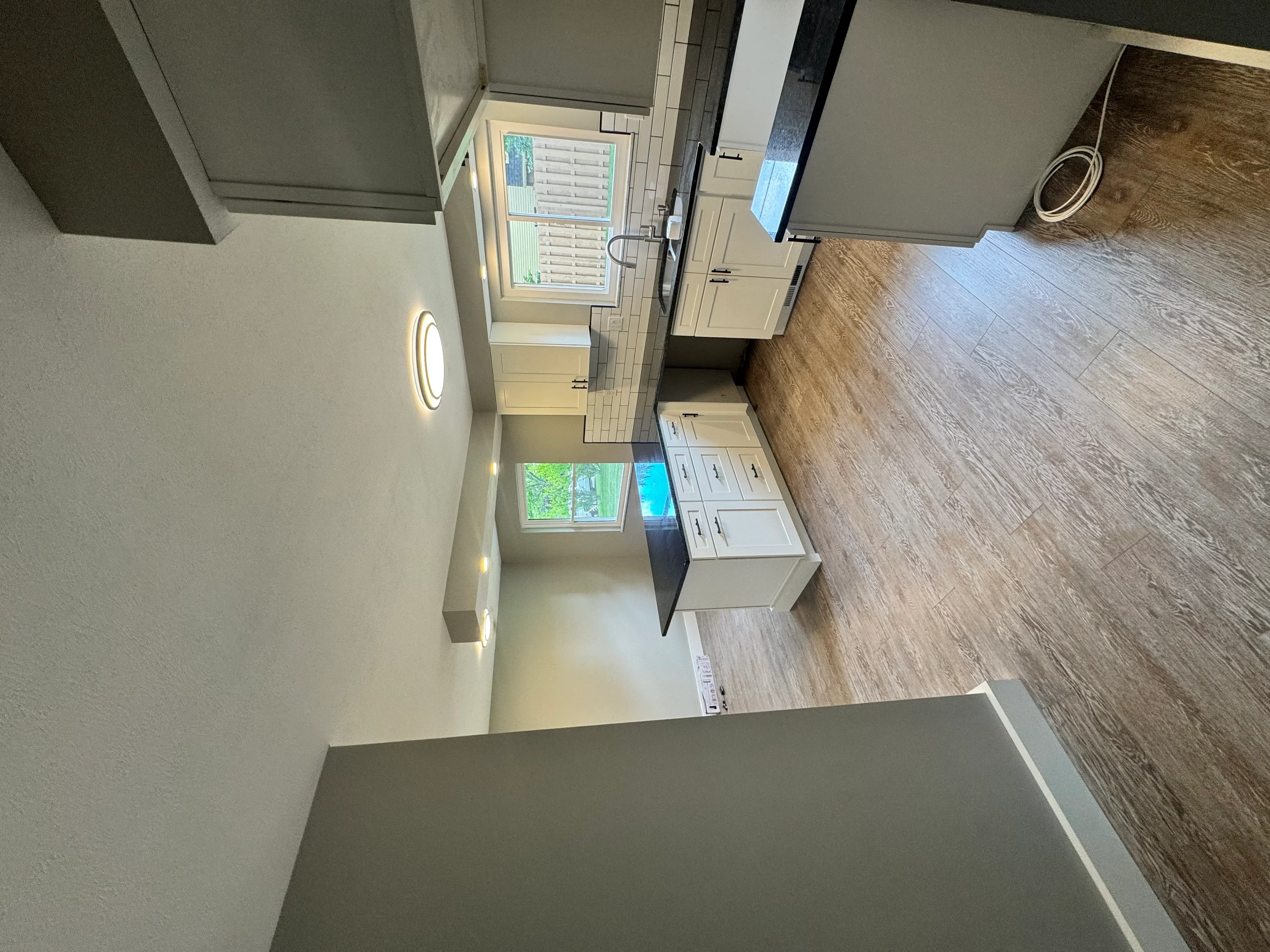 Renovated bathroom with wood-look flooring, white vanity, and tiled shower area