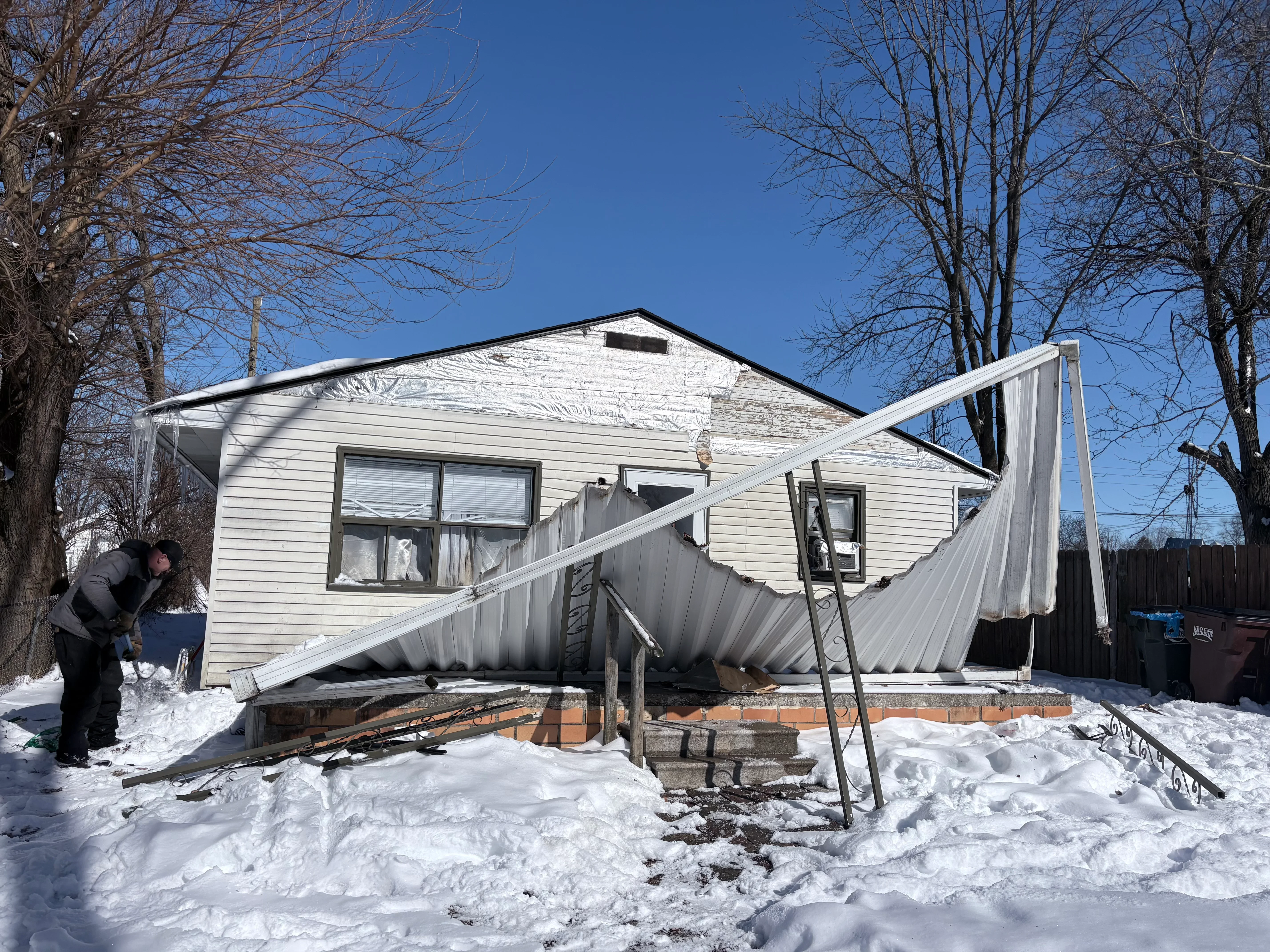 Mobile home with new white vinyl siding and metal roof during winter renovation project
