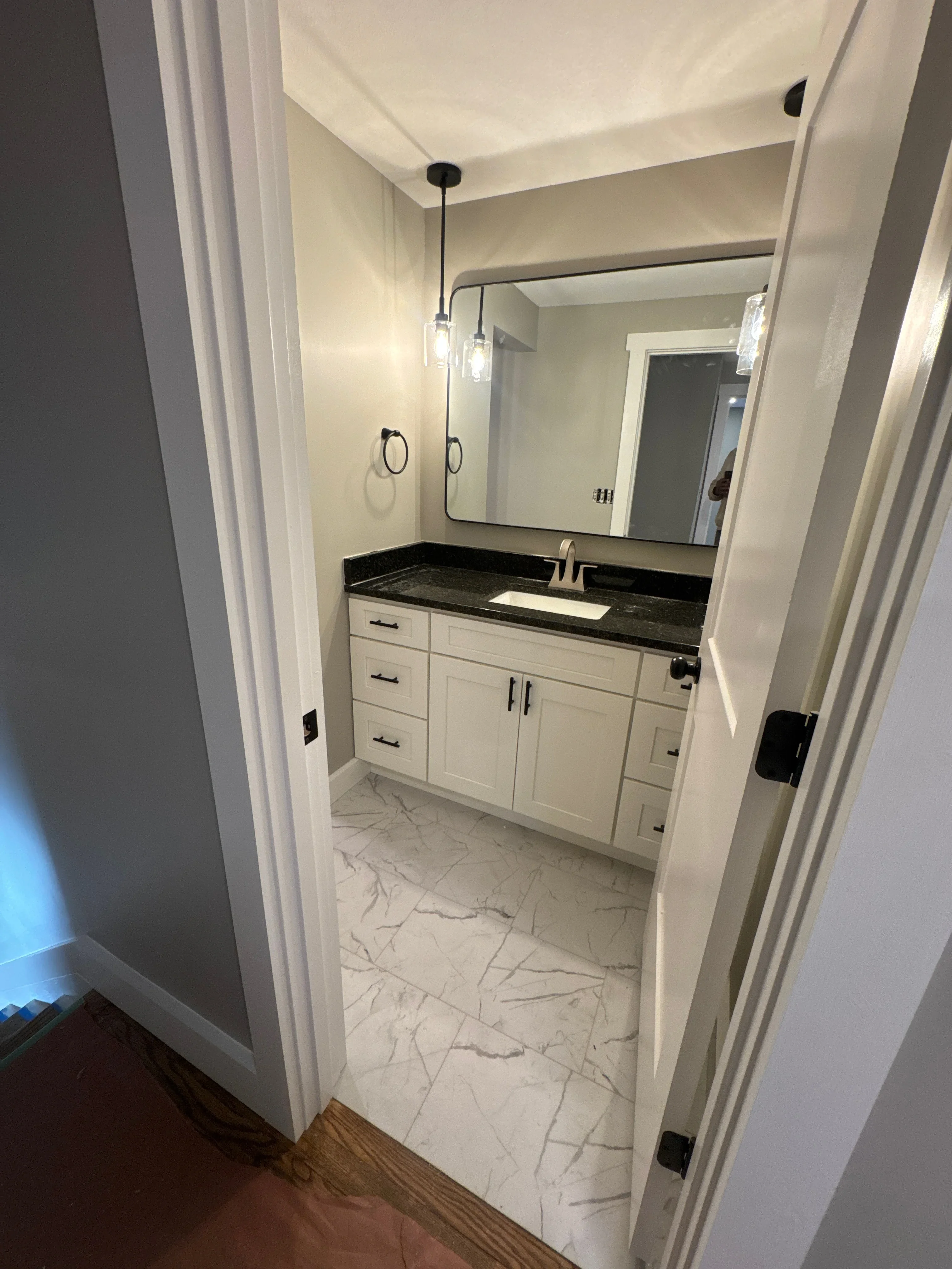 Modern bathroom vanity with white cabinets, black quartz countertop, and pendant lighting