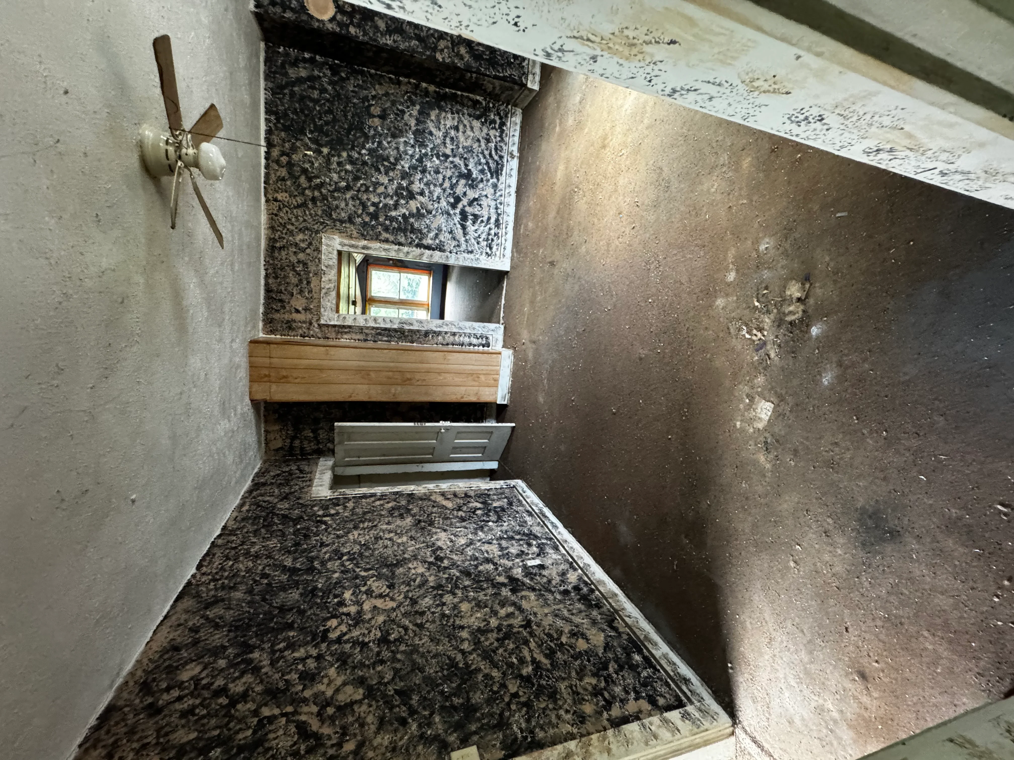 Interior demolition project showing exposed concrete floor and stripped walls in residential space