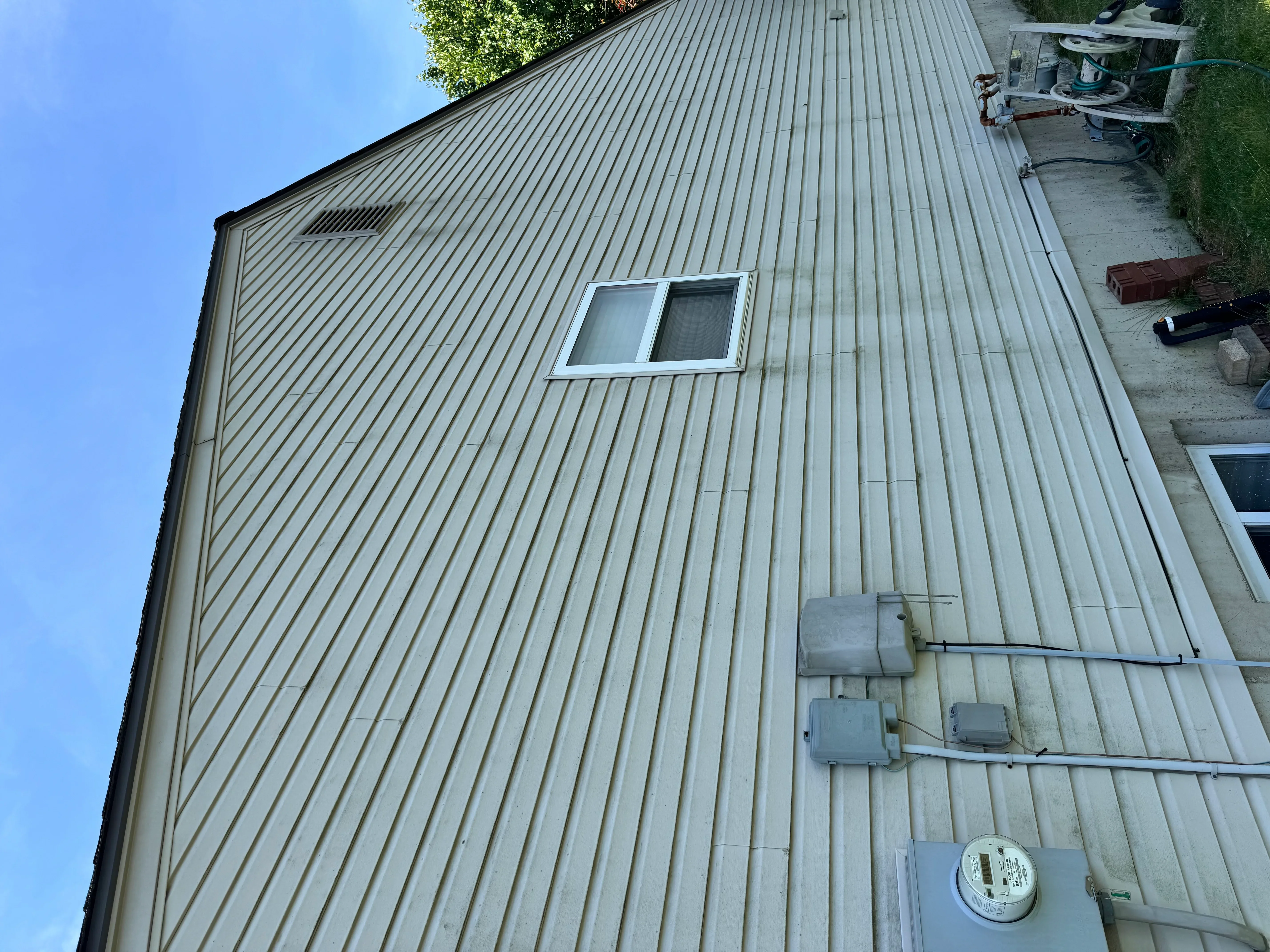 Metal siding installation with electrical conduit and window opening on residential building