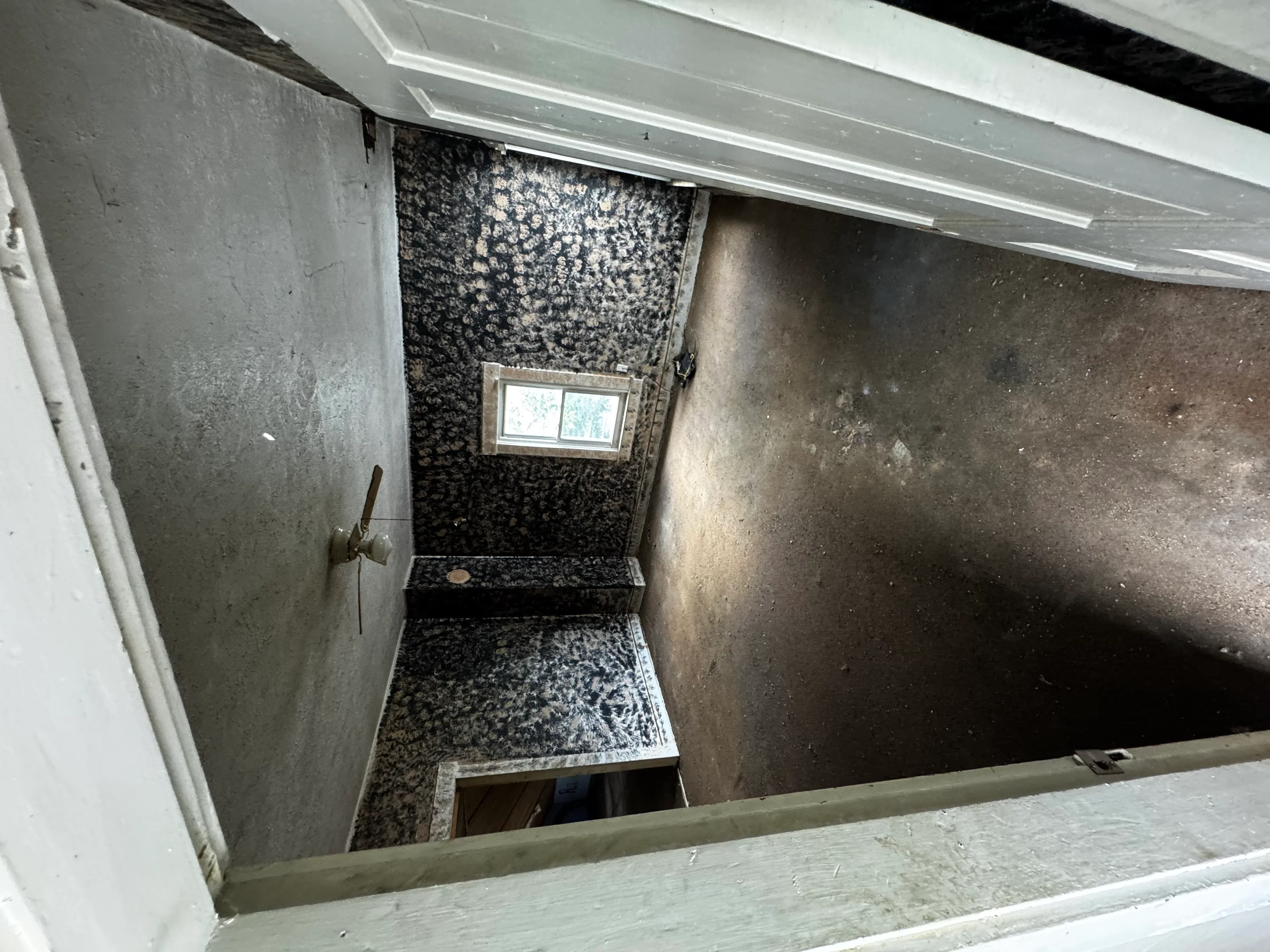 Newly installed basement shower with black speckled tile walls and floor, small window, and chrome fixtures