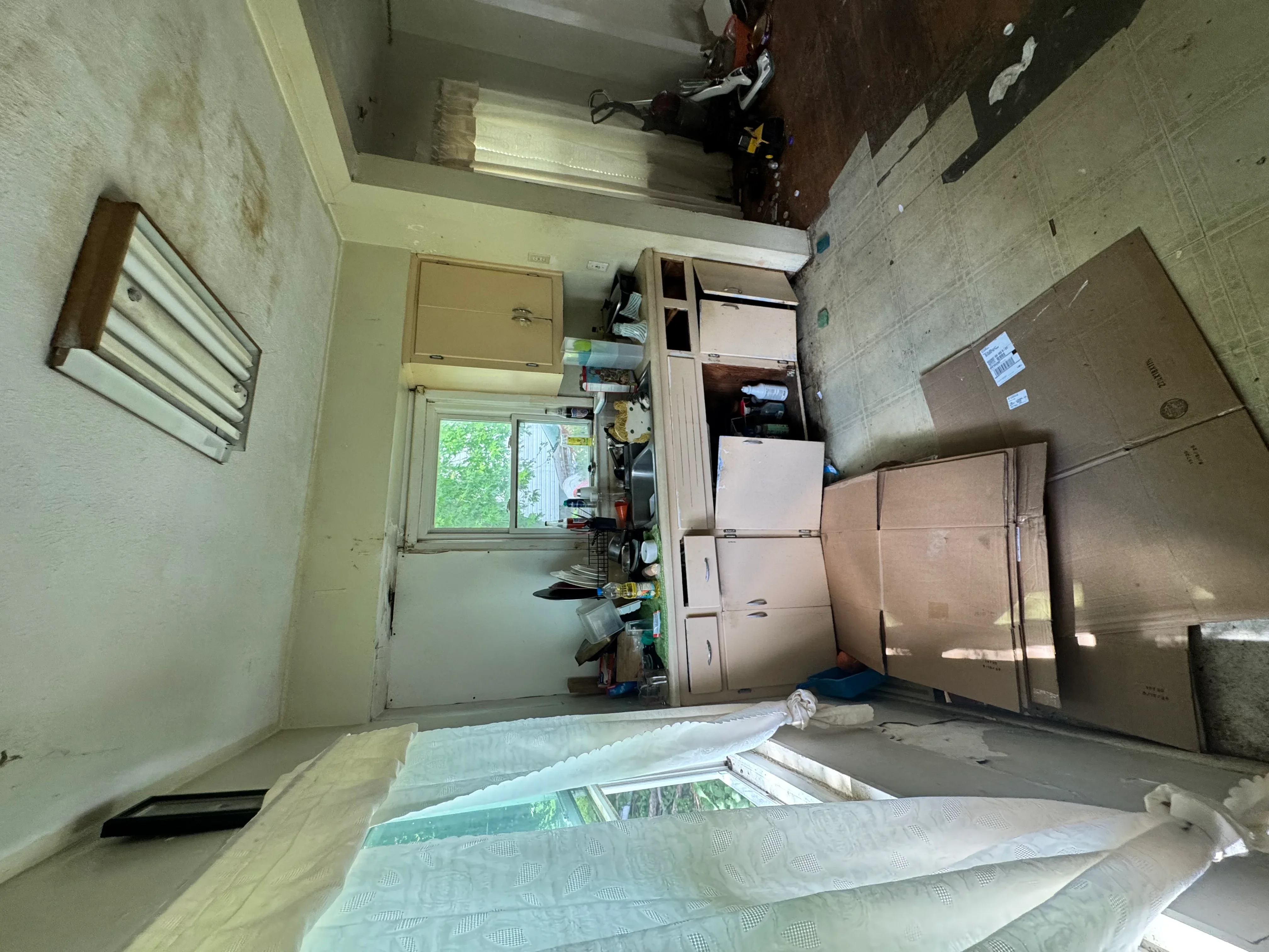 Empty room with removed cabinetry, cardboard boxes, and demolition debris during interior renovation