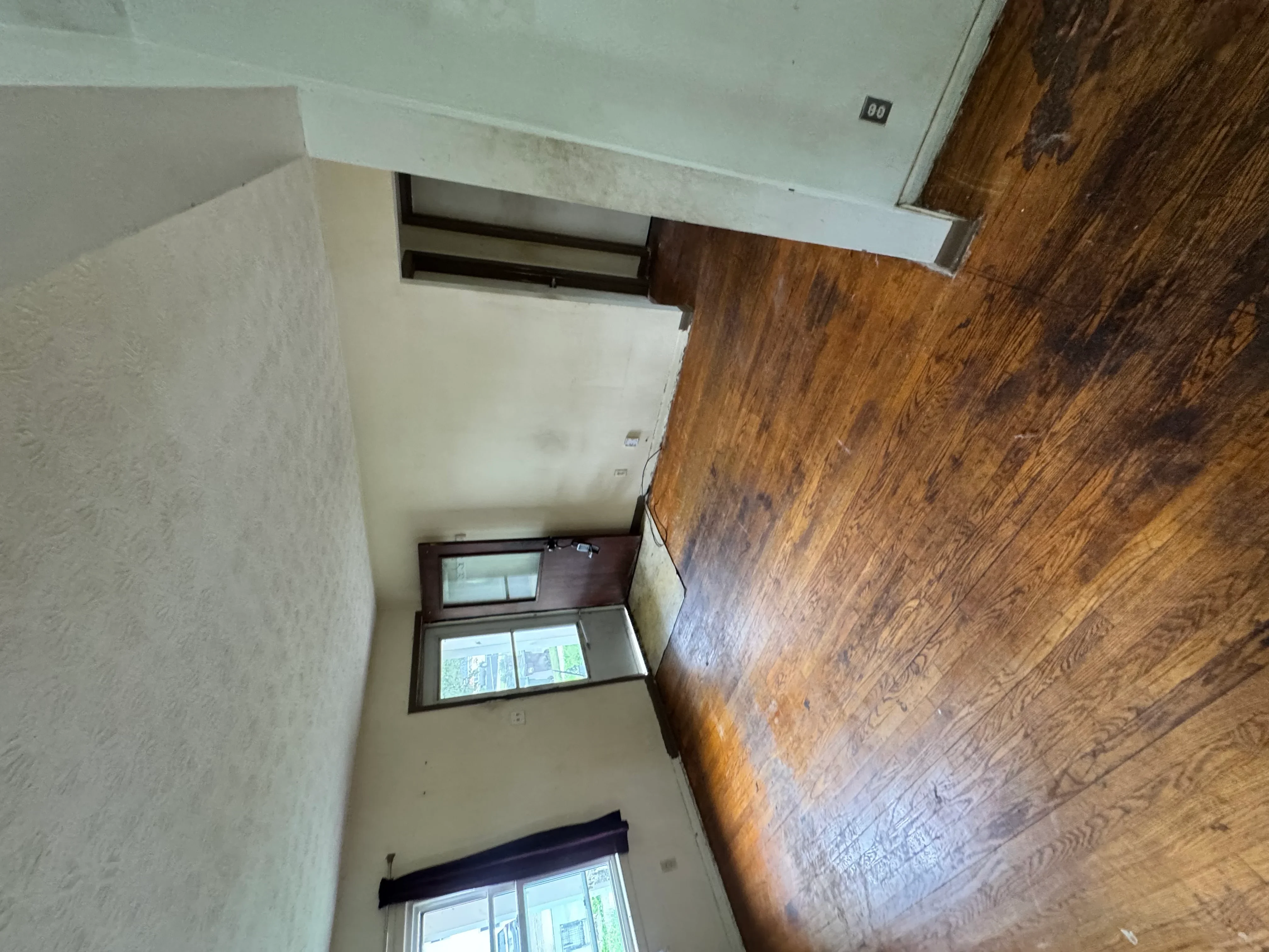 Newly installed hardwood flooring in room with white walls and dark wood trim