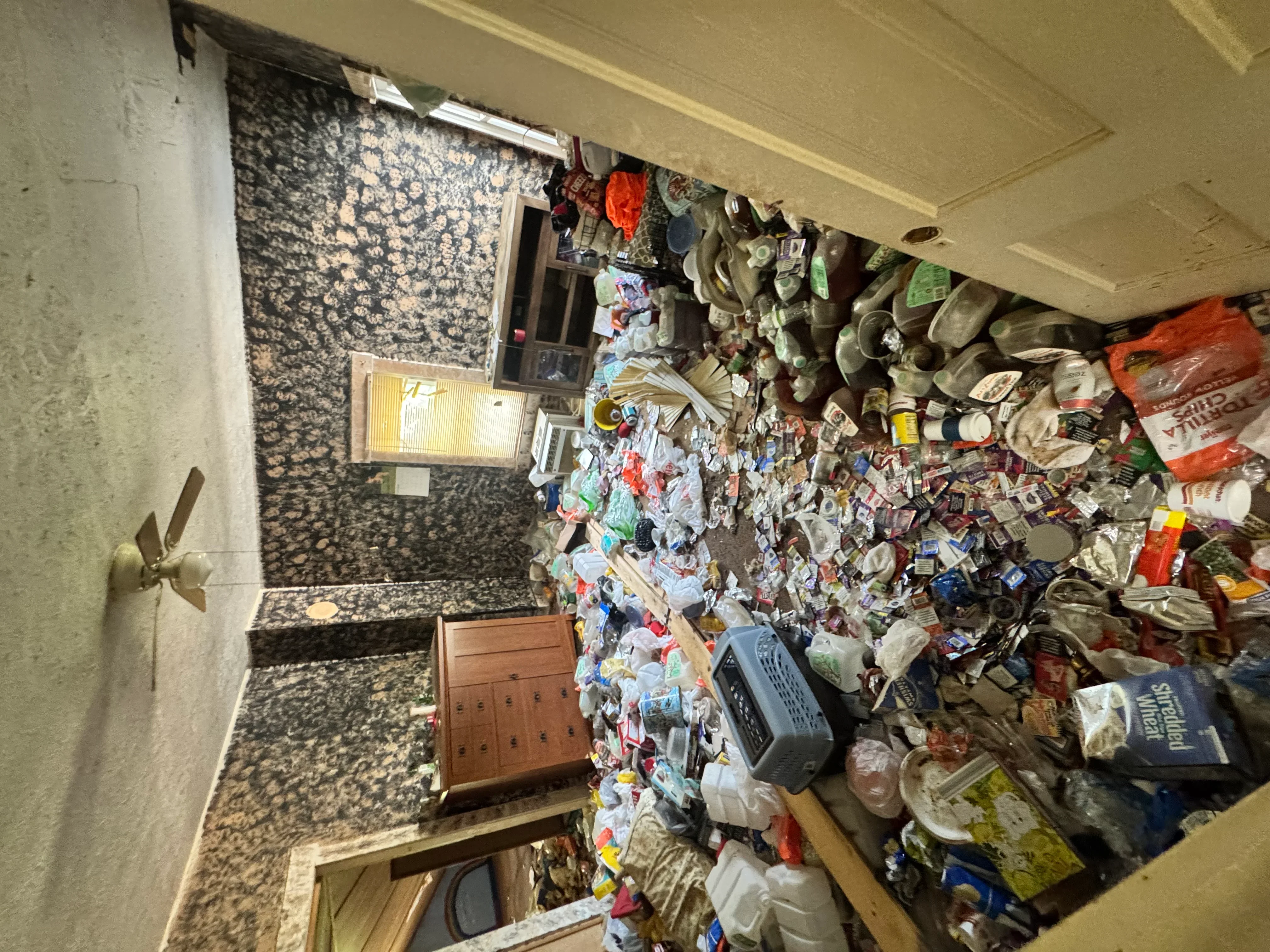 Before photo of cluttered residential room with accumulated items and debris requiring full cleanout