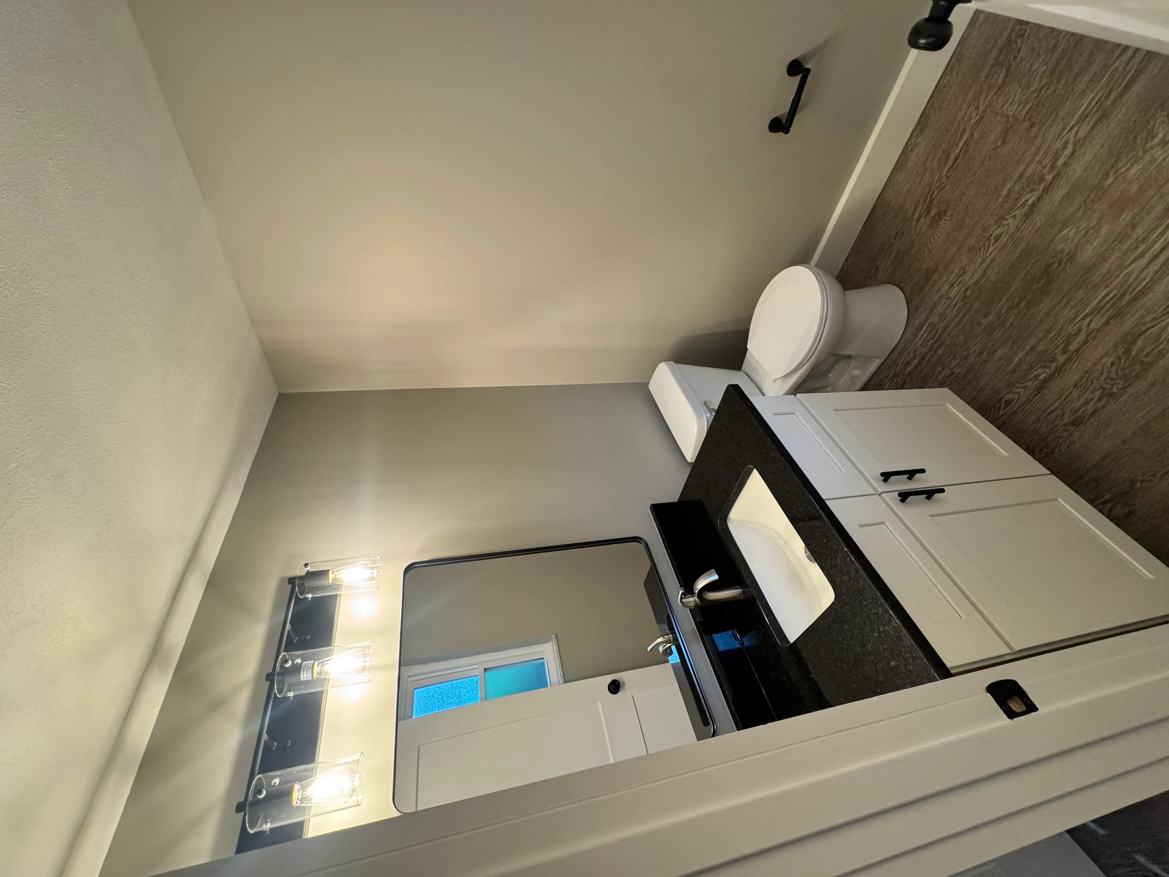 Modern bathroom with white vanity, wood-look flooring, and recessed lighting